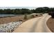 Scenic lake view with a curved driveway, lush greenery, and rock accents that enhance the natural beauty at 120 Bowfin Bay, Peachtree City, GA 30269