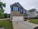 Charming two-story home features a two-car garage with stone accents and blue siding with an attractive lawn at 1946 Jeffery Nw Rd, Atlanta, GA 30318