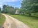 Long driveway leading to the stone house surrounded by mature trees and green lawns at 1085 Pleasant Hill Nw Rd, Conyers, GA 30012