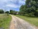 A view of the stone house at the end of a long driveway surrounded by green lawns at 1085 Pleasant Hill Nw Rd, Conyers, GA 30012