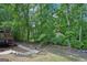 View of a wooded backyard featuring a deck, stone pathway, and mature trees providing ample shade at 765 Brooks Cir, Stone Mountain, GA 30087