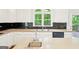 Modern kitchen with bright white cabinets, black backsplash, and stainless steel appliances at 765 Brooks Cir, Stone Mountain, GA 30087