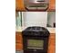 This kitchen features wood cabinets, a black stove, and stainless steel vent hood at 335 Cedar Ln, Fayetteville, GA 30214