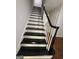 View of the staircase featuring black treads and white risers with wood flooring at 335 Cedar Ln, Fayetteville, GA 30214