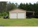 Outbuilding features a two-car garage and a covered bay for parking on a green lawn with wooded area at 124 Wynn Rd, Mcdonough, GA 30252