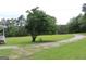 View of the side yard featuring green grass, large tree, and gravel driveway at 124 Wynn Rd, Mcdonough, GA 30252