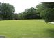 Expansive green yard and gravel driveway leading to wooded area in the background at 124 Wynn Rd, Mcdonough, GA 30252