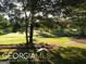 Expansive backyard with lush green grass, mature trees, and a tranquil pond view at 531 Grant Rd, Brooks, GA 30205