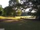Expansive green lawn leading to a peaceful pond surrounded by mature trees at 531 Grant Rd, Brooks, GA 30205