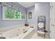 Blue bathroom featuring a large tub with jets, window, and decorative accents at 9255 Betony Wood Trl, Jonesboro, GA 30236