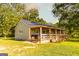 Exterior view of a charming cabin with a long, inviting porch and beautiful green surroundings at 316 Gaithers Rd, Mansfield, GA 30055