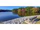 Scenic lake view with a bench along the rocky shoreline and colorful trees in the background, offering a relaxing retreat at 101 Sumner Place Ct, Peachtree City, GA 30269
