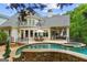 Inviting backyard with stone-lined pool, patio seating, outdoor lounge, and upper level balcony at 8957 Old Southwick Pass, Johns Creek, GA 30022