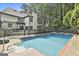 A pristine in-ground pool with ladder and diving board, surrounded by lush greenery and a fenced perimeter at 209 Smokerise Trce, Peachtree City, GA 30269