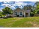 The tan home features large white trimmed windows, green yard and beautiful landscaping at 255 Mcintosh Estates Dr, Sharpsburg, GA 30277