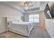Bright main bedroom featuring a tray ceiling, soft carpet, and a large window with a view of the outdoors at 1005 Belfry Ter, Fairburn, GA 30213
