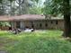 Backyard with overgrown grass and brick home with trash and debris at 4116 Warrior Trl, Stone Mountain, GA 30083
