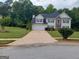 Beautiful two-story home featuring a manicured lawn, two-car garage, stone accents, and a long driveway at 75 Trelawney Keep, Covington, GA 30016