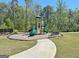 A community playground with slides, climbing features, and a bench surrounded by lush greenery and a black fence at 510 Cunninghame Ct, Peachtree City, GA 30269
