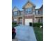 A townhouse featuring mixed exteriors: brick, stone, tan painted siding, with blue shutters and an attached garage at 5257 Carrie Dr, Morrow, GA 30260
