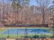 Outdoor tennis court with a vibrant blue surface, surrounded by lush trees and well-lit with lamps at 4213 Bretdale Nw Run, Kennesaw, GA 30152
