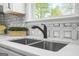 Close-up of a modern stainless steel kitchen sink with matte black faucet and decorative tile backsplash at 474 Autumn Dr, Riverdale, GA 30274