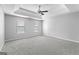 Large carpeted bedroom featuring tray ceilings, a ceiling fan, and two windows at 4506 White Rd, Douglasville, GA 30135
