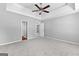 Carpeted bedroom with tray ceilings, ceiling fan and a view of a connecting hallway at 4506 White Rd, Douglasville, GA 30135