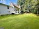 Large backyard with green grass and a two-story white house and back patio at 110 Shelby Oaks Trl, Covington, GA 30016