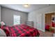 A cozy bedroom featuring a red and black patterned duvet cover, a window, and a white shelf at 4752 Albany Way, South Fulton, GA 30331