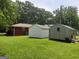 Backyard showcasing multiple storage sheds on a grassy lawn, surrounded by mature trees at 856 New Hope Rd, Fayetteville, GA 30214