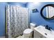 Cozy blue bathroom featuring a shower with patterned curtain, toilet, and modern vanity at 5780 Pumkintown Rd, Douglasville, GA 30135
