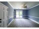 Bright bedroom featuring carpet, light blue walls, and a ceiling fan with large windows at 5780 Pumkintown Rd, Douglasville, GA 30135