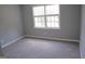 Well-lit bedroom with neutral carpet, gray walls, and a large window with views of the outdoors at 74 Flanders Ct, Douglasville, GA 30134