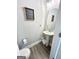 Neutral-toned bathroom features a pedestal sink, round mirror, and framed motivational art at 7728 Fawn Cir, Covington, GA 30014