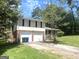 Side view of two-story home with a two car garage, an extended porch, and mature landscaping at 443 S Rays Rd, Stone Mountain, GA 30083