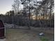 Expansive backyard with scattered trees, partial fencing, a propane tank, and a glimpse of a barn at 5700 Miles Rd, South Fulton, GA 30349