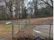 Fenced backyard with sparse grass, a propane tank, trees, and a glimpse of a distant structure at 5700 Miles Rd, South Fulton, GA 30349