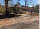 Image shows a carport with a red roof, metal beams and concrete pad surrounded by a treed lot at 5700 Miles Rd, South Fulton, GA 30349