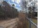 Image shows land with exposed dirt road and fencing in the foreground with trees in the background at 5700 Miles Rd, South Fulton, GA 30349