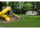 Spacious backyard featuring a playground set, shed, lush green grass, and mature trees at 5113 Heritage Oaks Sw Ln, Powder Springs, GA 30127