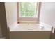 Serene bathroom featuring a corner jetted tub with a garden view at 5113 Heritage Oaks Sw Ln, Powder Springs, GA 30127