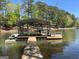 Covered boat dock on a peaceful lake featuring boat and jet ski lifts and ample seating at 921 Oak Dr, Woodstock, GA 30189