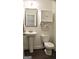 Small half bathroom featuring a pedestal sink, toilet, and decorative wall cabinet at 878 W Union Grove Cir, Auburn, GA 30011