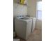 A clean and functional laundry room features a washer, dryer and shelving for storage at 878 W Union Grove Cir, Auburn, GA 30011