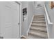 A carpeted staircase with white railing leads to the upper level, showcasing natural light and neutral décor at 150 Cold Harbor Ct, Sharpsburg, GA 30277