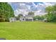 Large backyard view from patio with lawn, white home exterior, storage shed, and mature trees at 503 Atwood Cir, Peachtree City, GA 30269
