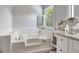 Relaxing bathroom with a soaking tub, white tile, and a bright, shuttered window at 503 Atwood Cir, Peachtree City, GA 30269