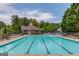 Community pool with multiple lanes and lounge chairs, with a pool house and wooded area in the background at 2990 Haynes Club Cir, Grayson, GA 30017