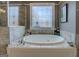 Bathroom featuring a luxurious soaking tub, tiled shower, and frosted windows, offering a spa-like retreat at 4128 Hunt Sw St, Covington, GA 30014